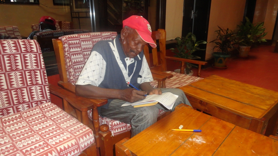 Mzee Mbaso Rowili writing a Taveta story during the Taveta Orthography Workshop